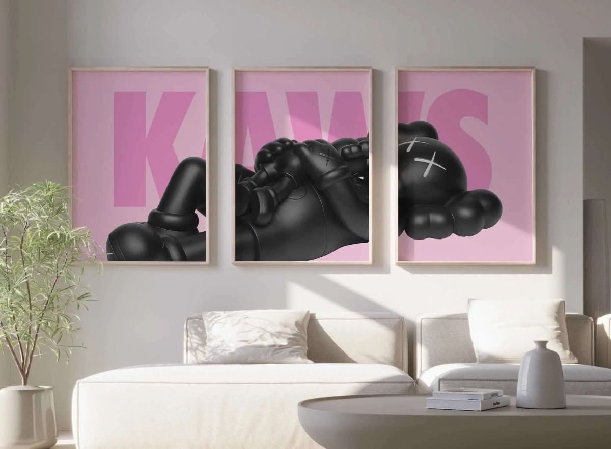 Black KAWS figure resting on pink background, with the word "KAWS" prominently displayed in modern typography.