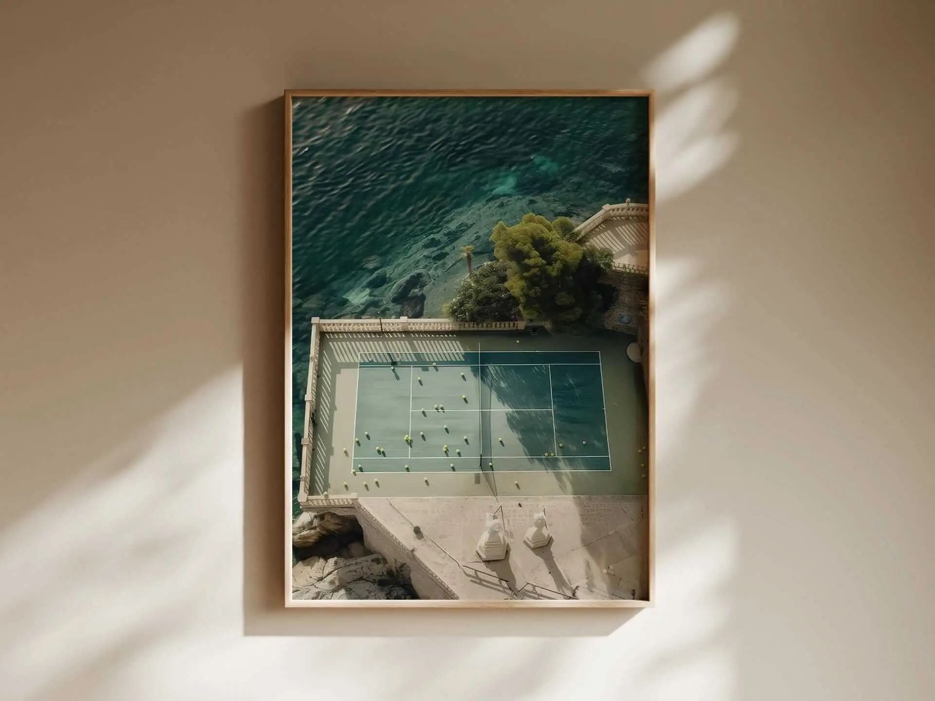 Aerial view of a tennis court surrounded by water and greenery framed as wall art in a minimalist room