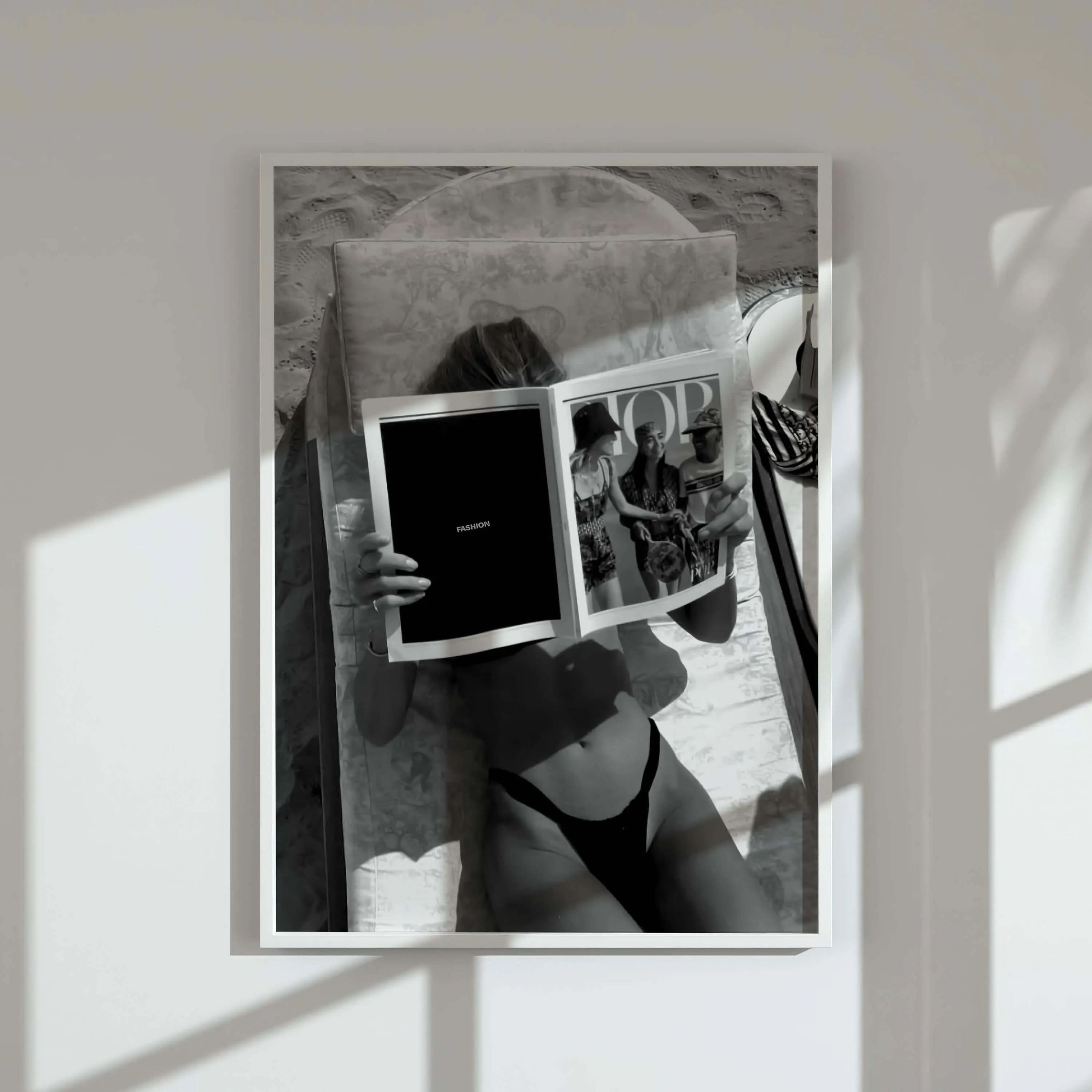Black and white vintage fashion photography print of woman reading Vogue magazine on beach chair, printable wall art by Haus of Prints.