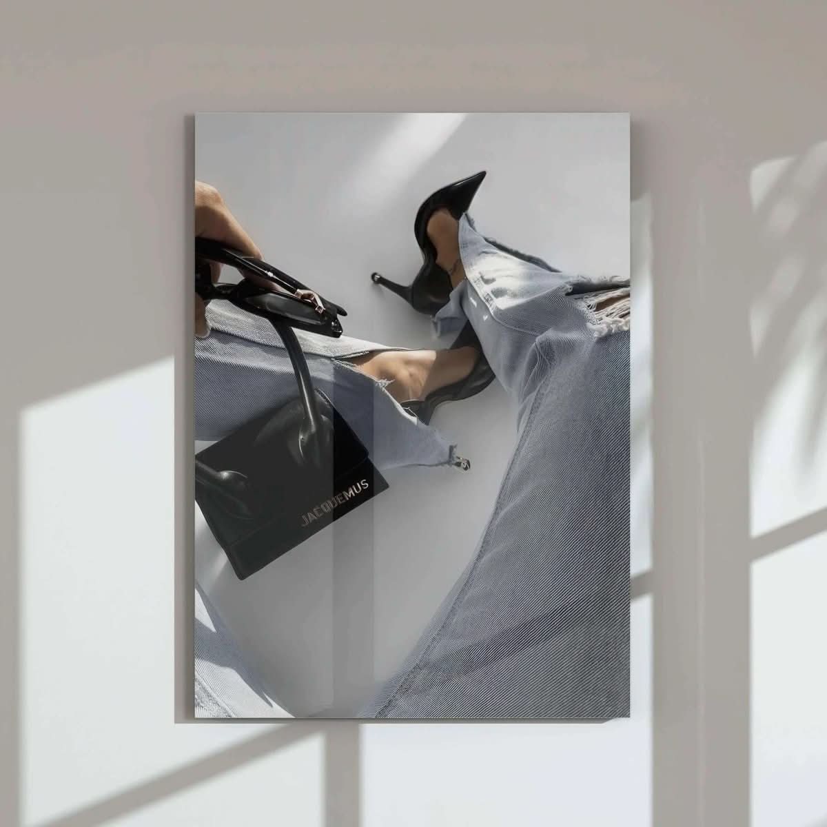 Elegant female leg in ripped jeans and high heels, with a designer bag in hand.