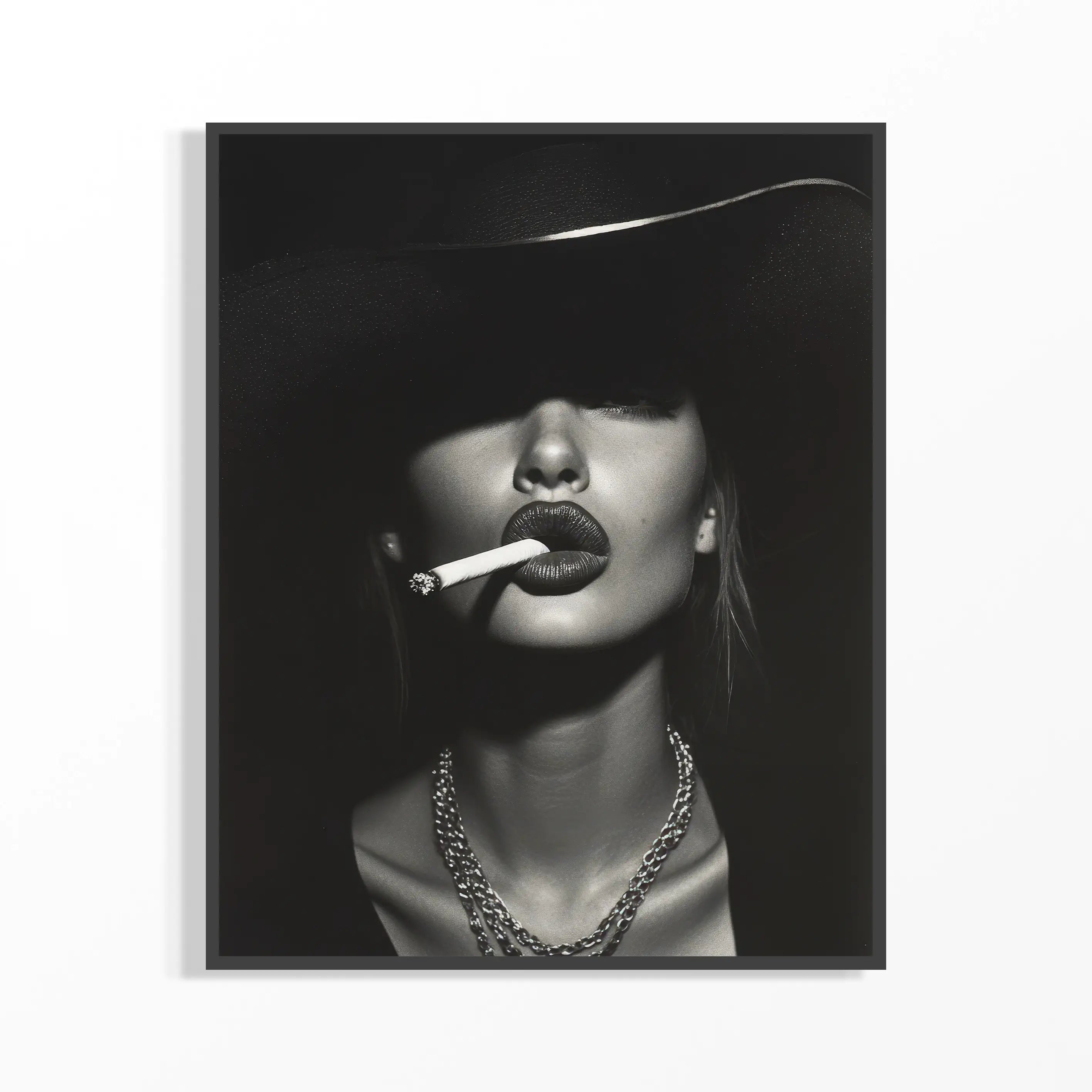 Black and white portrait of a Kate Moss wearing a wide-brimmed hat, smoking a cigarette.
