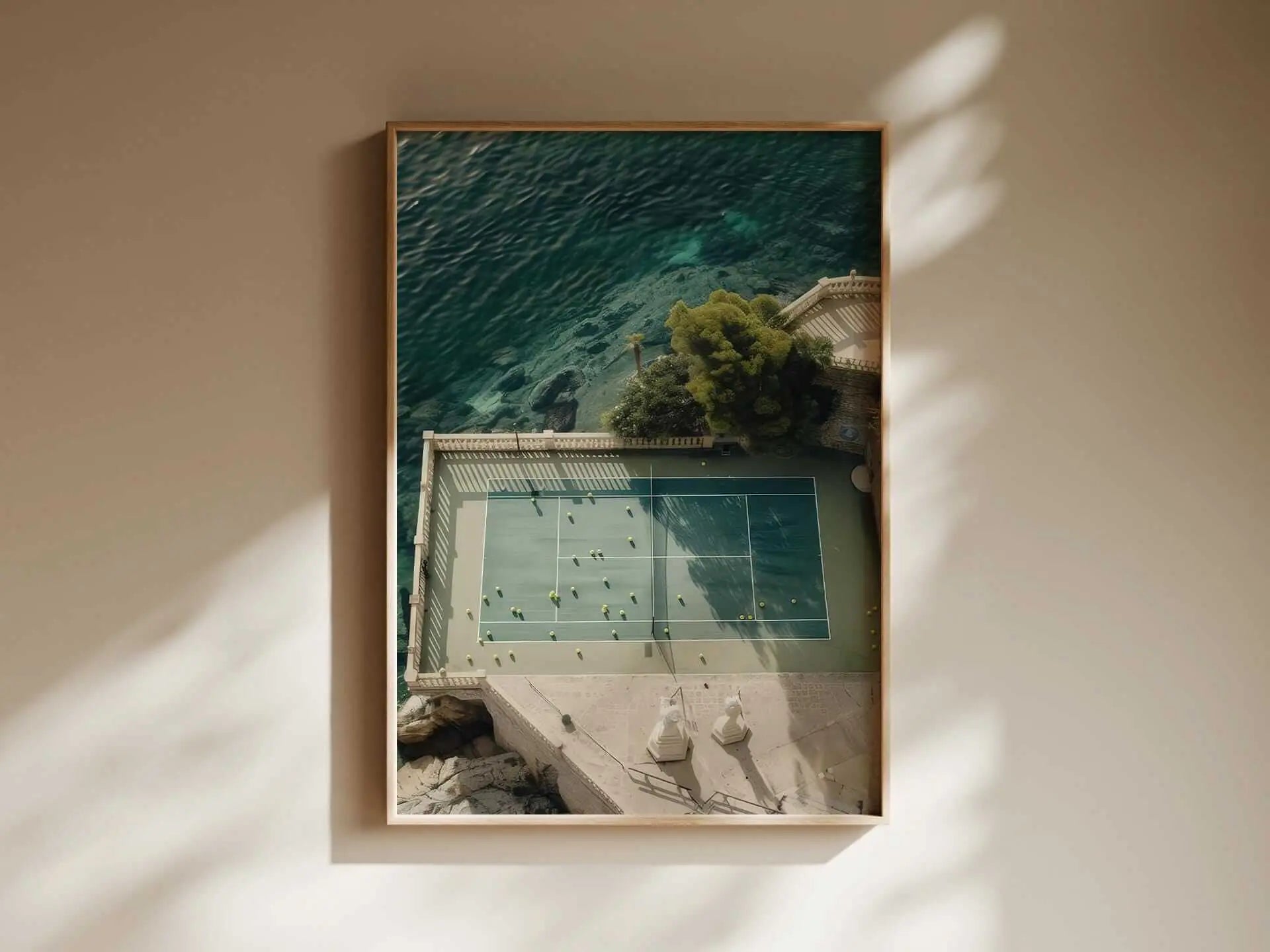 Aerial view of a tennis court surrounded by water and greenery framed as wall art in a minimalist room