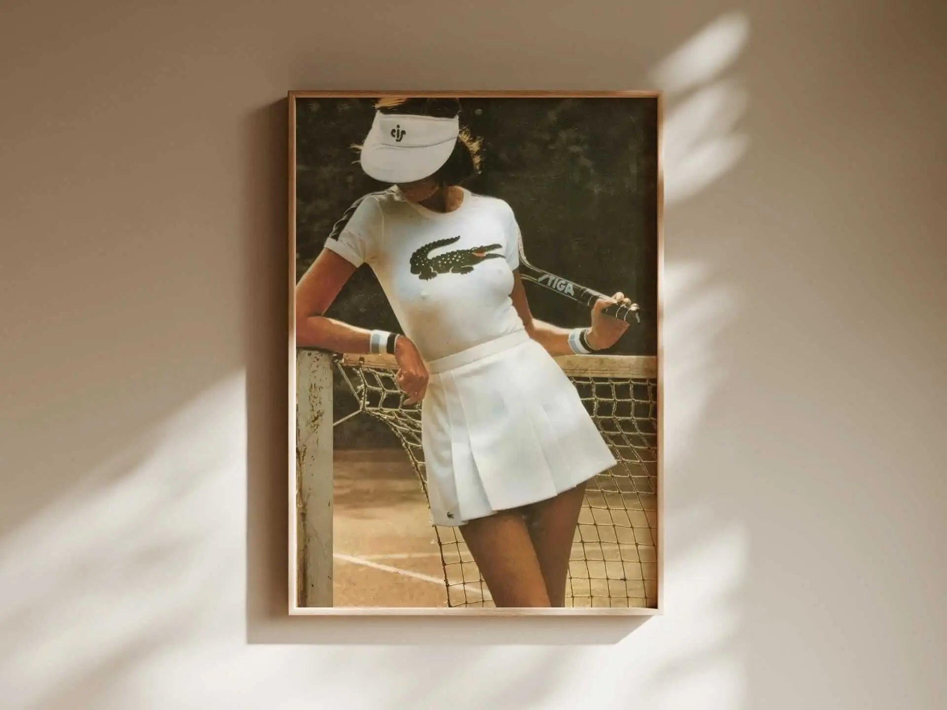 Tennis wall art featuring a female player leaning on a net in vintage white tennis attire and visor